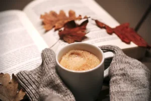 person wearing sweater and holding hot drink